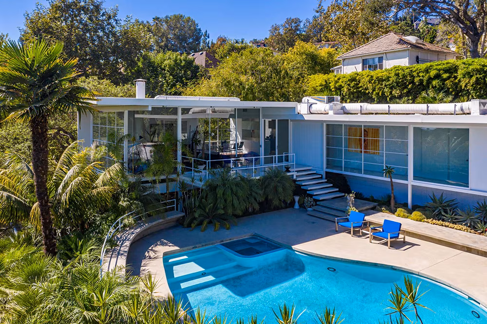 Exterior view of Brad Pitt’s former Los Feliz Steel House featuring its modernist architecture, swimming pool, and lush hillside surroundings.