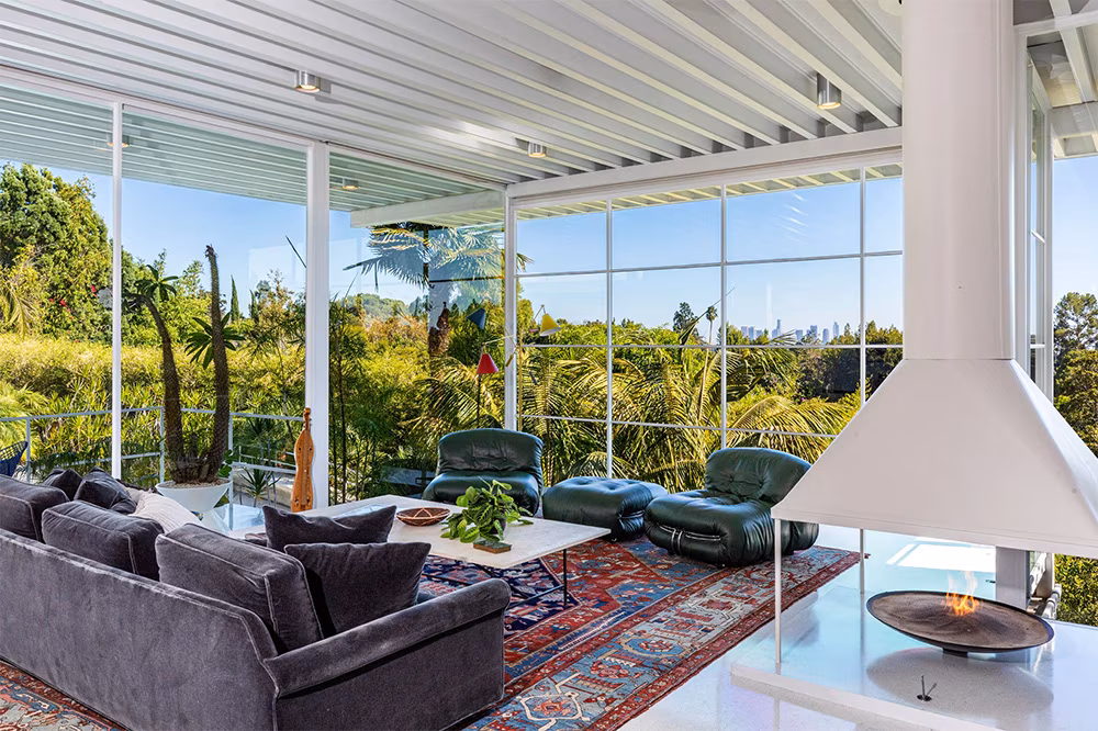 Interior of Brad Pitt’s former Steel House living area with floor-to-ceiling glass walls, beamed ceilings, and terrazzo floors.