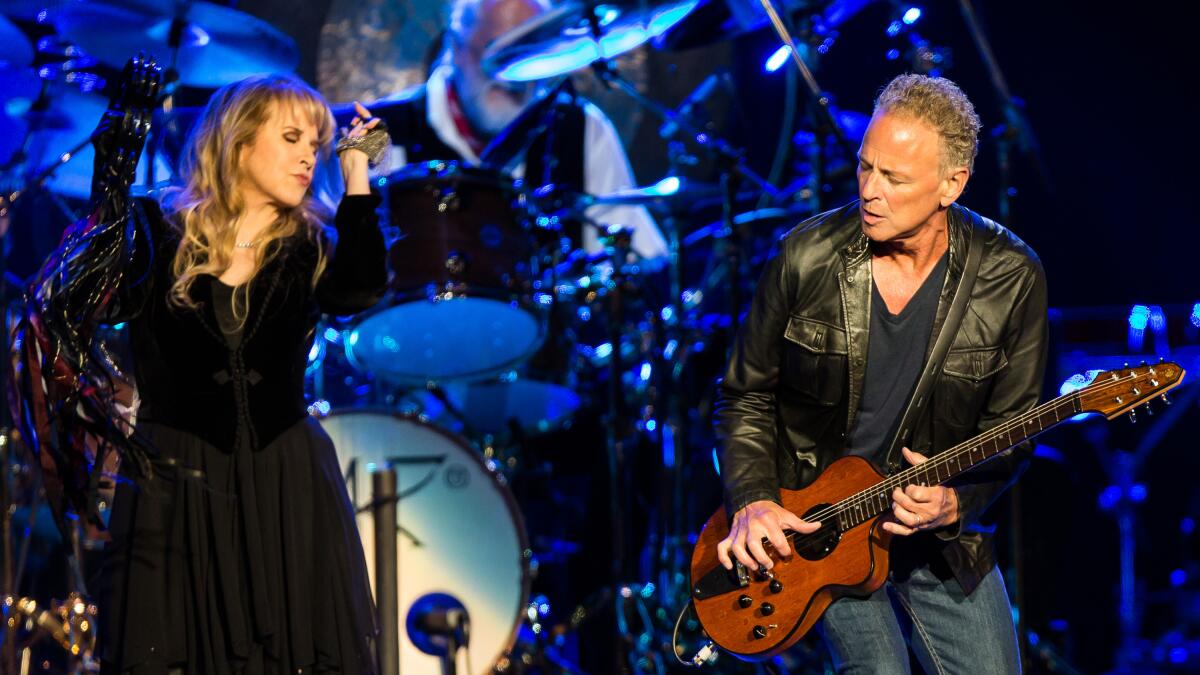 Stevie Nicks and Lindsey Buckingham performing together on stage during a Fleetwood Mac concert.