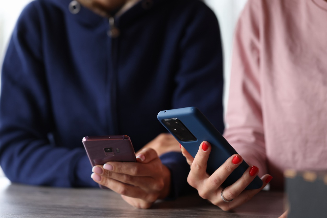 two women are holding smartphones in their hands.