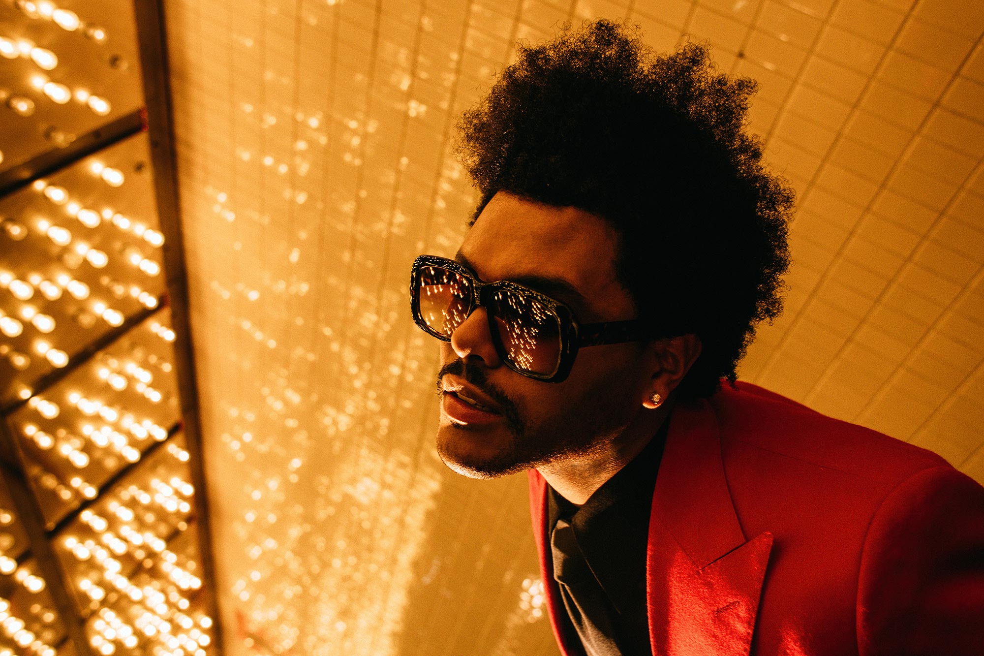 The Weeknd performing “Blinding Lights” on stage under dramatic red and white lighting.