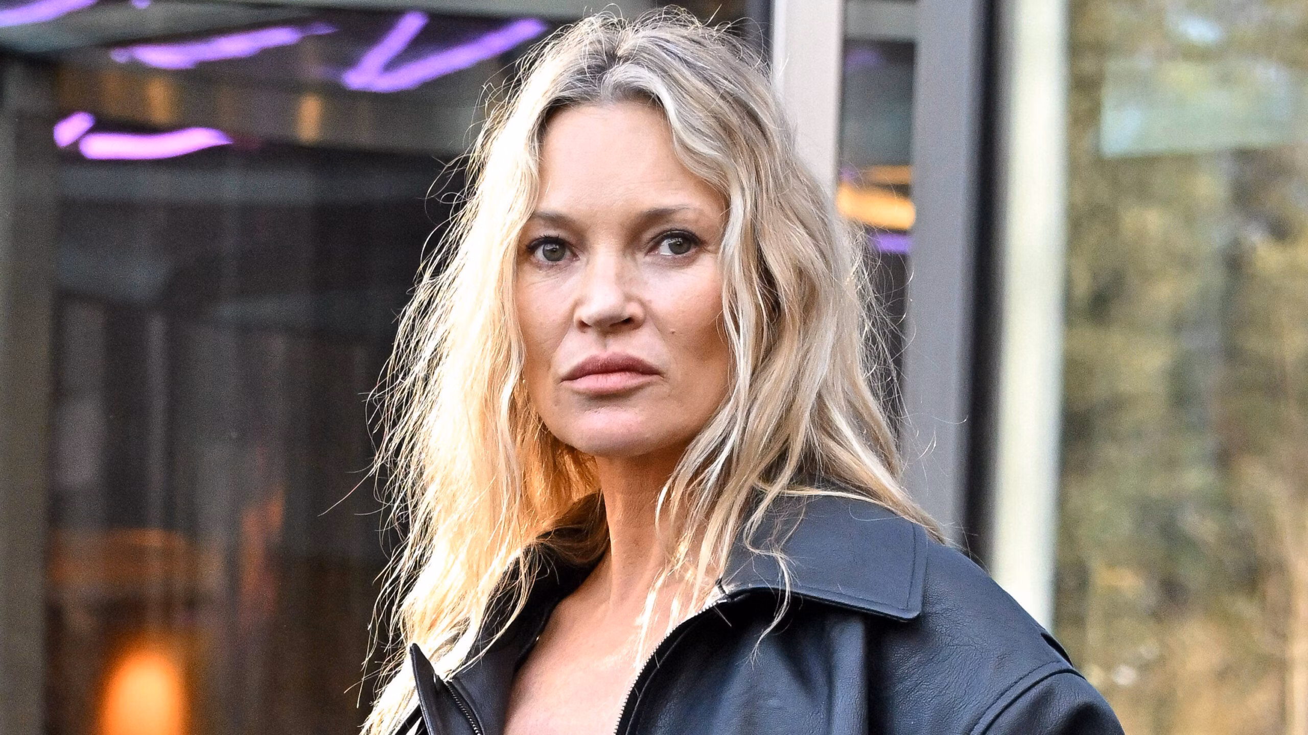 Kate Moss shopping on the high street, wearing a leather jacket and looking serious.