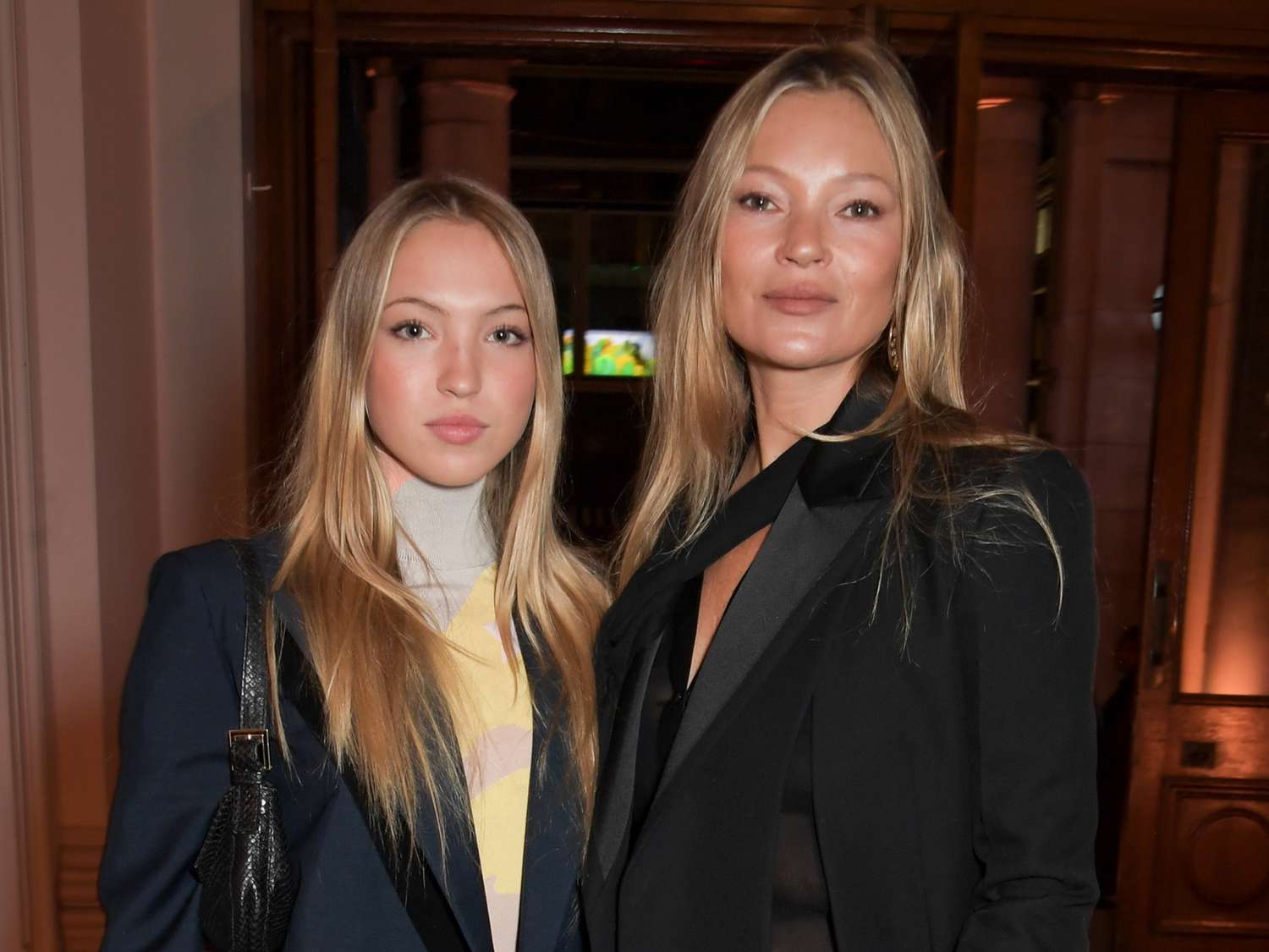 Kate Moss posing for a photo with her daughter, both smiling and dressed stylishly.