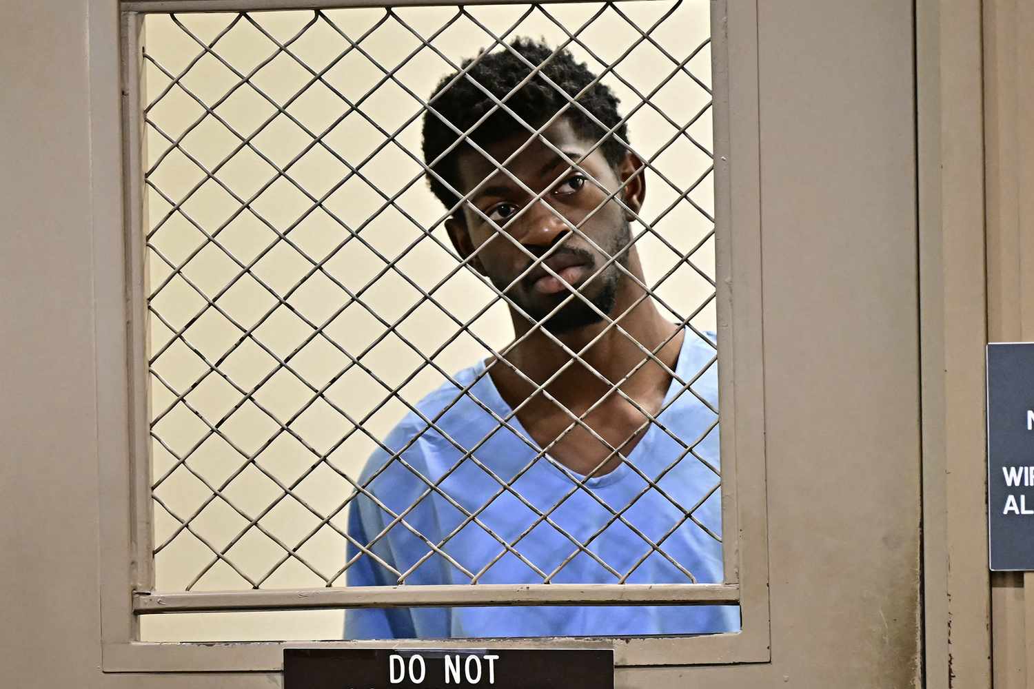 Lil Nas X peering through a holding cell window, anxiously awaiting release.