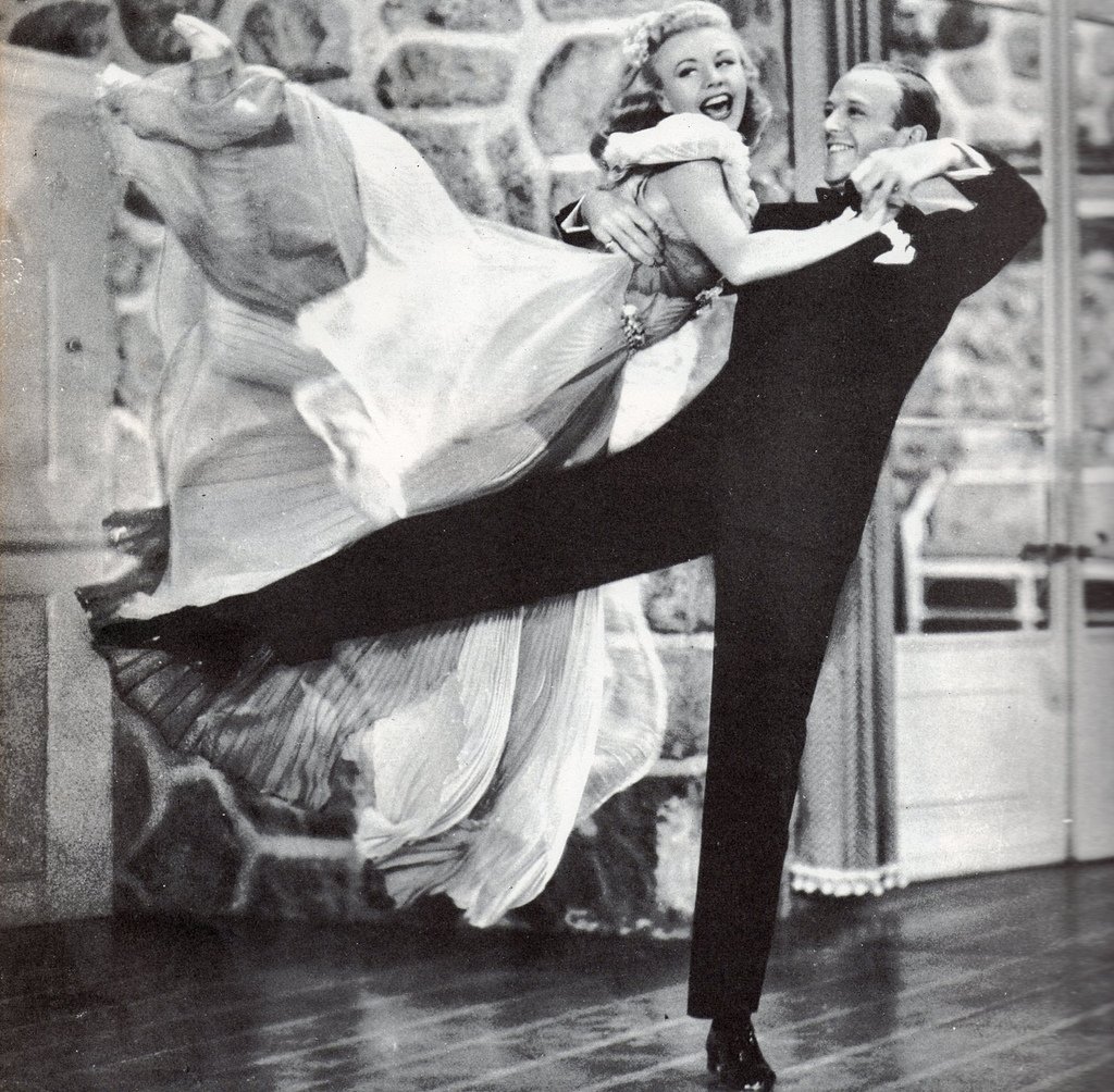 Ginger Rogers and Fred Astaire performing an iconic dance routine on stage, showcasing their legendary chemistry and elegant style.