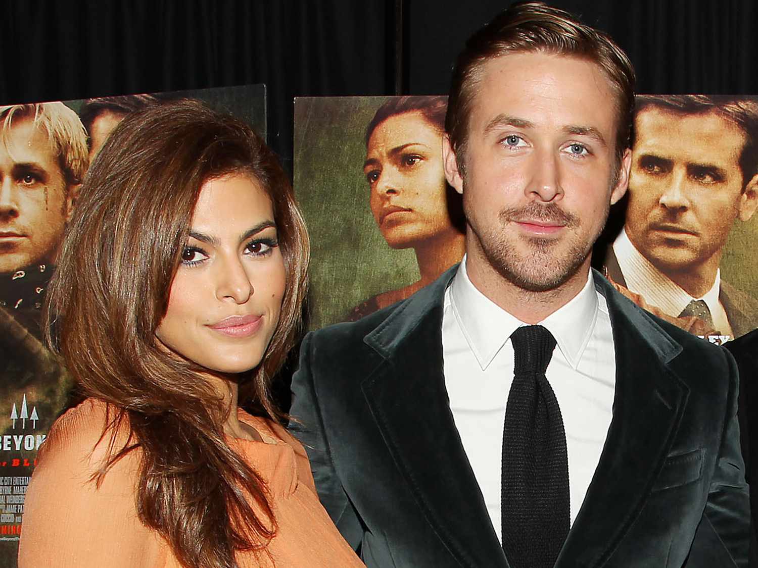 Eva Mendes and Ryan Gosling posing together, smiling, and dressed elegantly on the red carpet.