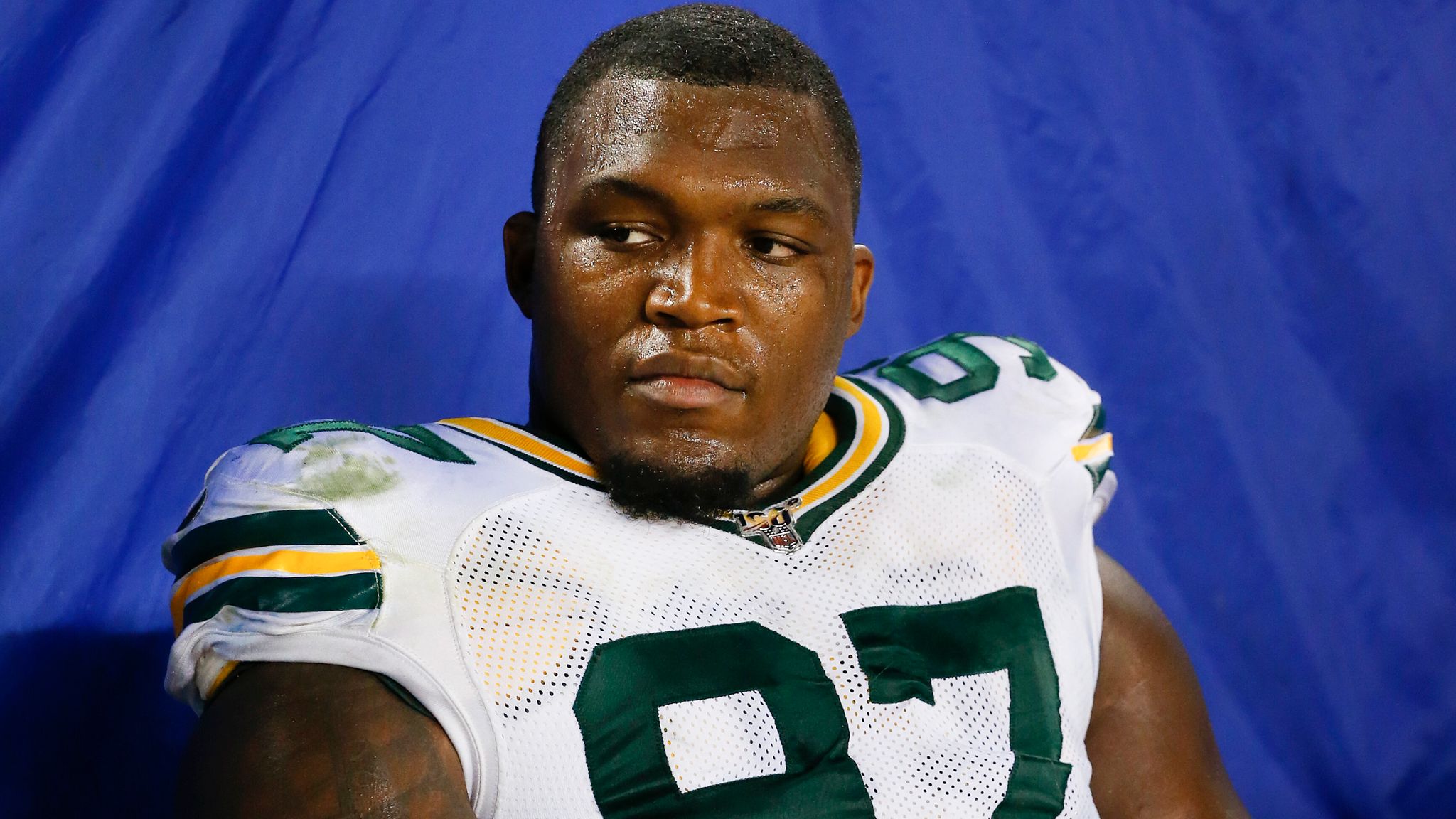 Kenny Clark sitting on the bench with a serious expression during a game.