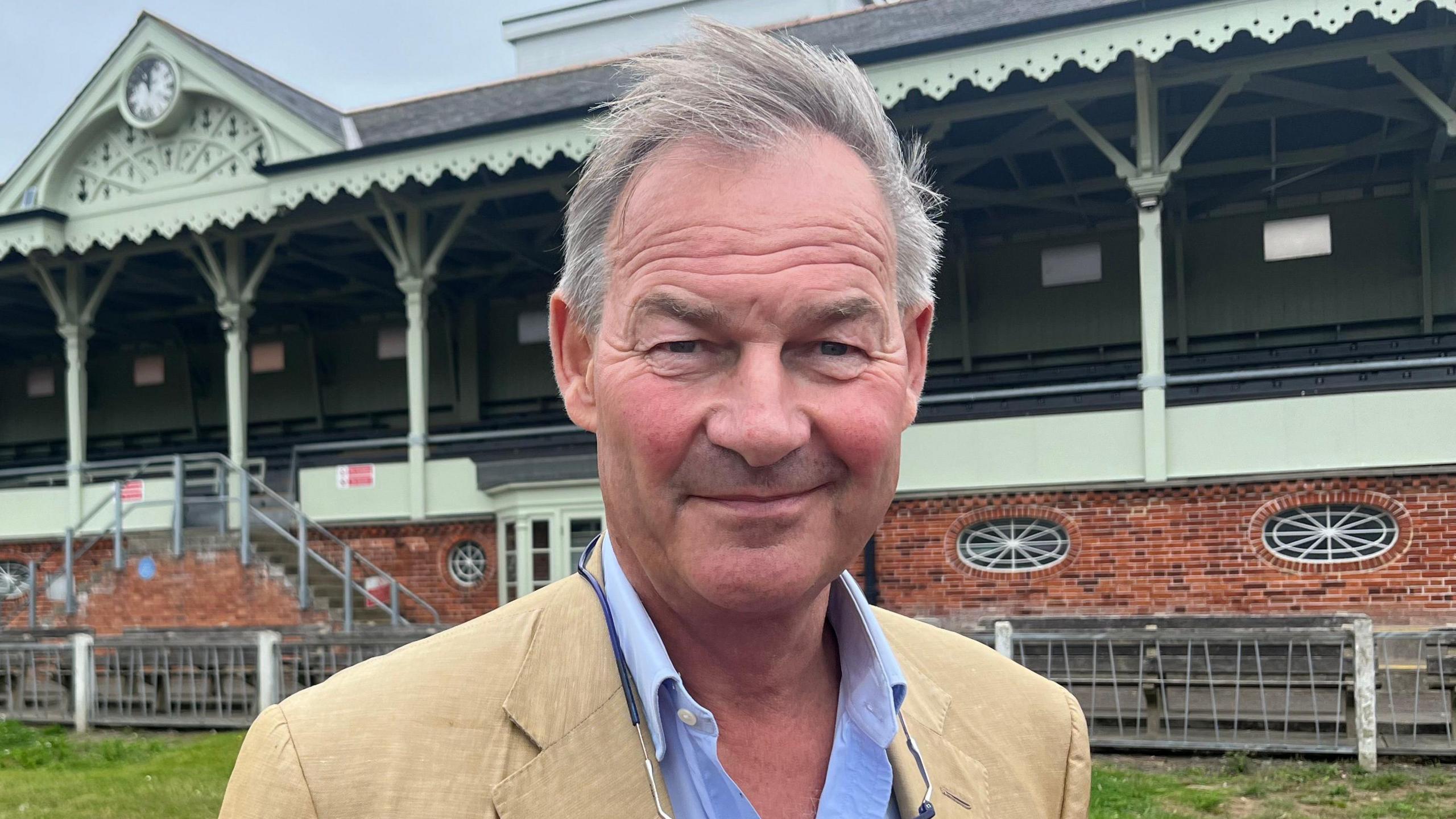 Rupert Lowe smiling for the camera at a horse racing event, dressed in formal attire.