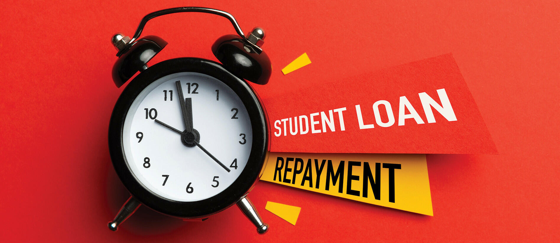Alarm clock with the words “Student Loan Repayment” displayed against a bright red background, symbolizing urgency.