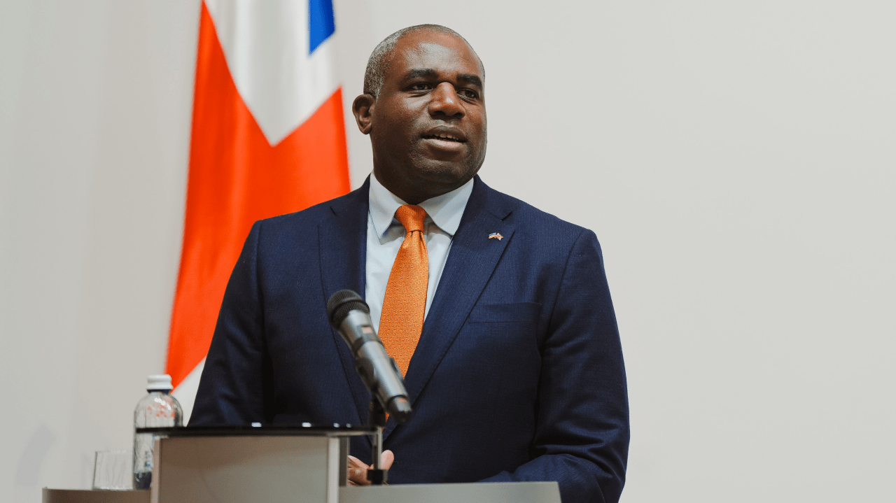 David Lammy delivering a speech at a podium with the Union Jack behind him.