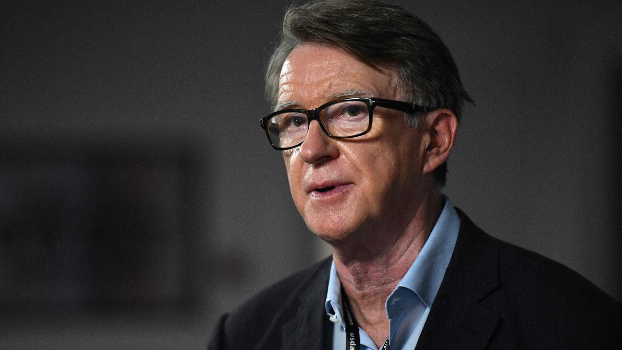 Peter Mandelson being interviewed in a darkly lit studio, speaking seriously while seated.