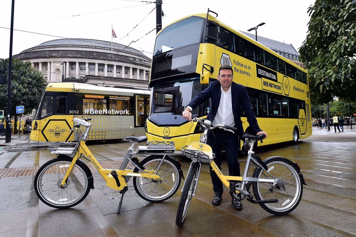 Andy Burnham posing with buses and bicycles in Greater Manchester, highlighting his commitment to improving public transport and sustainable mobility.
