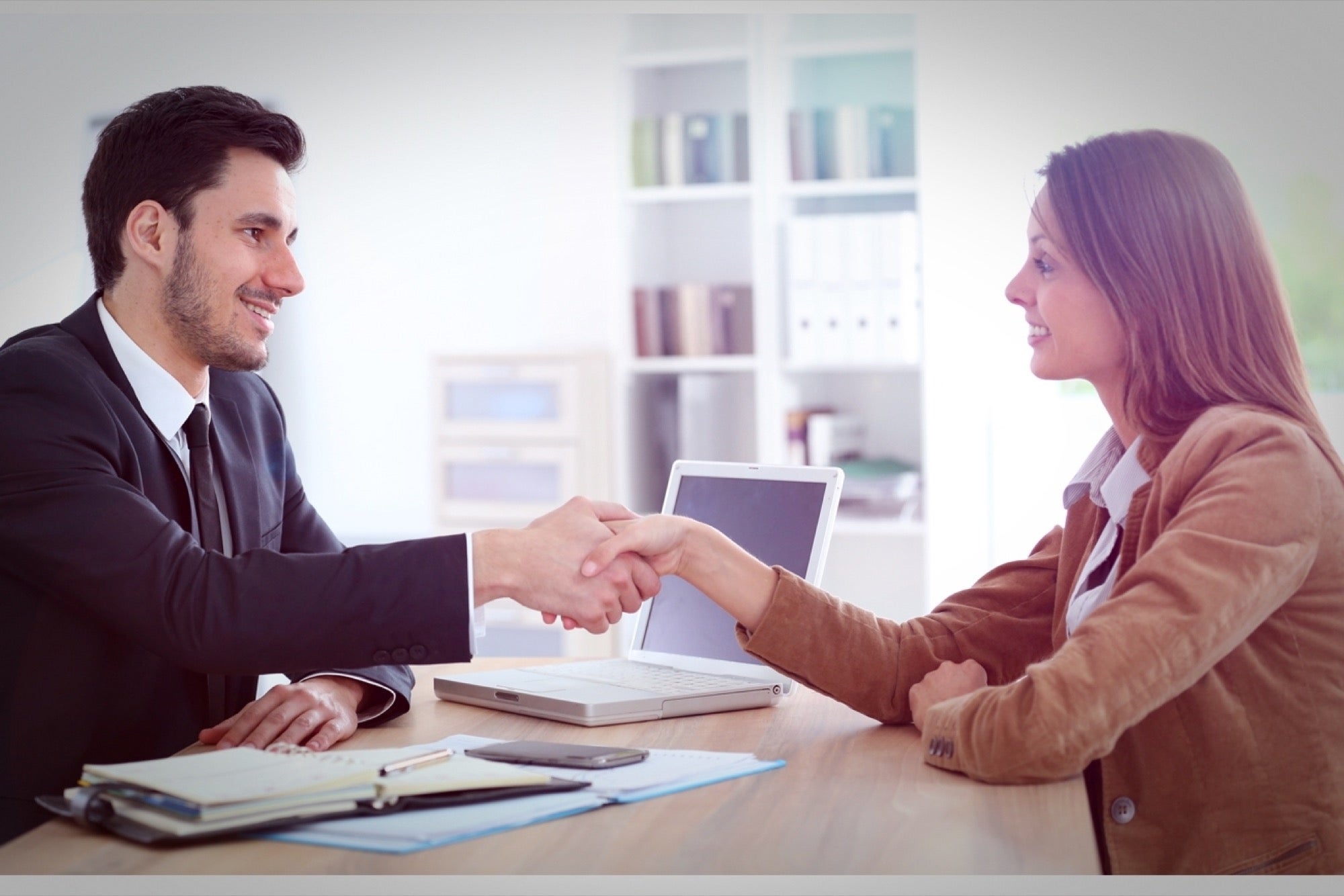 A bank manager shaking hands with a businesswoman after approving her business loan, symbolizing successful financing and partnership.