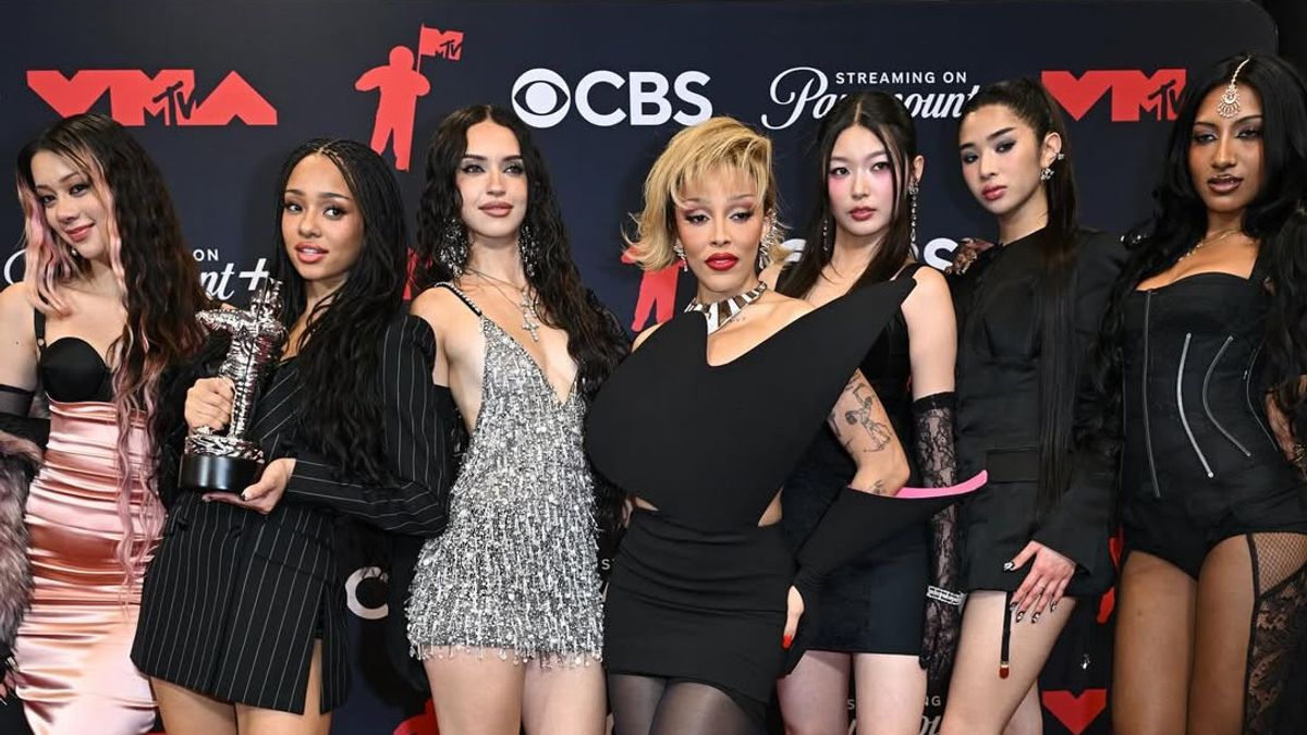 A line of celebrities posing and walking on the red carpet at a glamorous awards event, with photographers in the background.