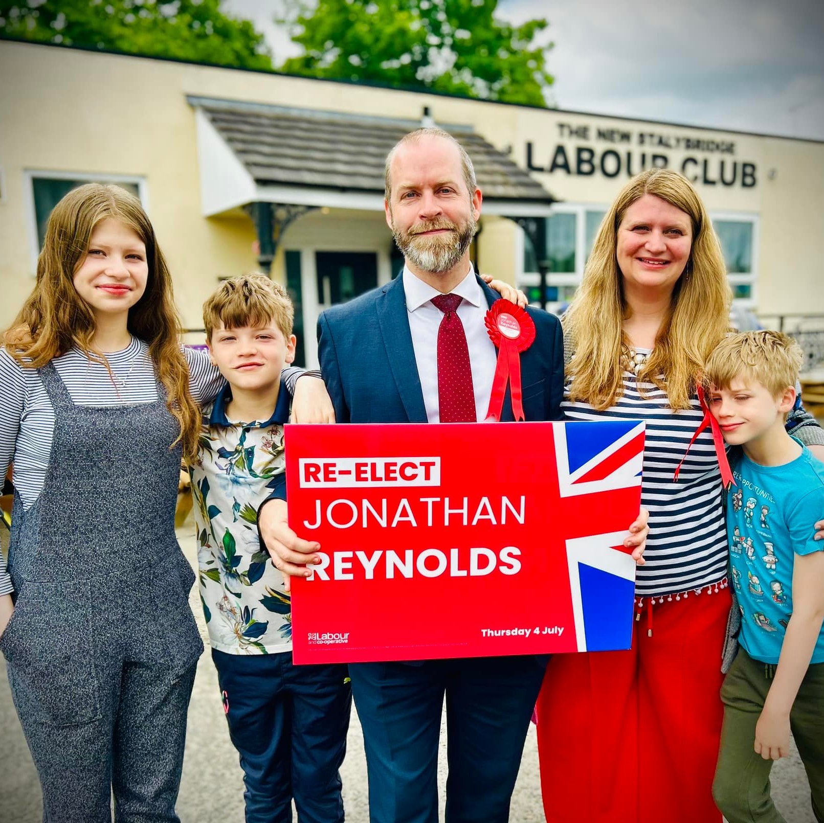 Jonathan Reynolds with his wife and children, holding a campaign sign and celebrating his election victory.