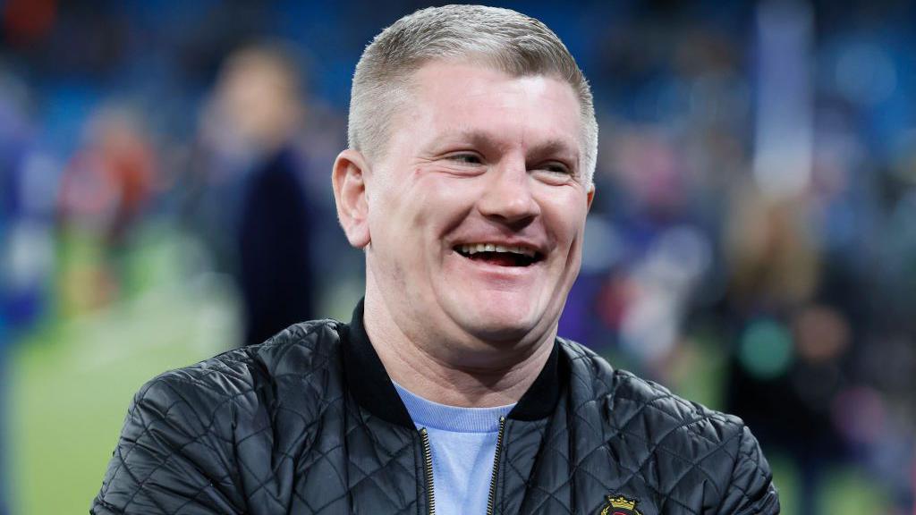 Ricky Hatton attending a Manchester City football game, wearing casual attire and cheering from the stands.