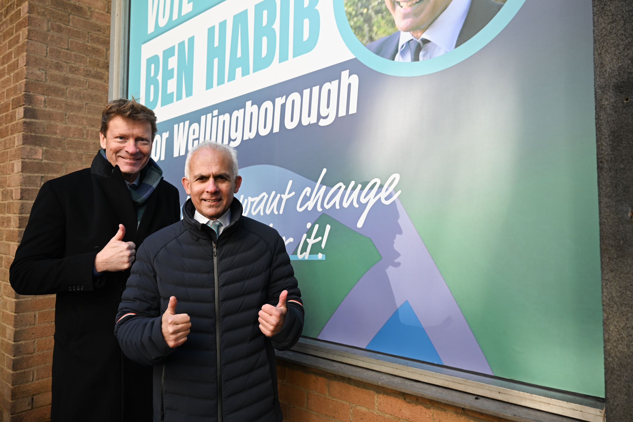 Ben Habib and Richard Tice standing together on the campaign trail, posing beside a Reform UK poster.