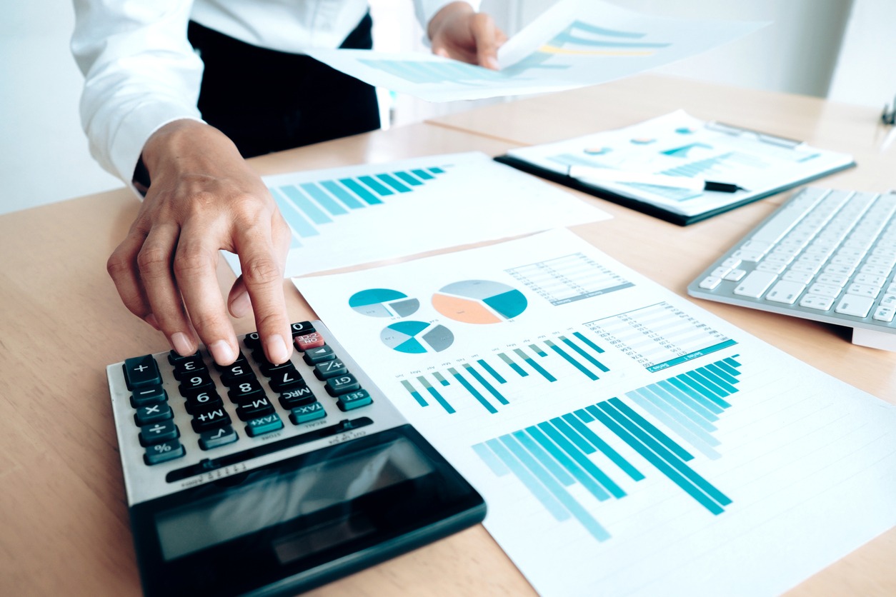 An accountant analyzing pie charts and using a calculator to evaluate a business loan.