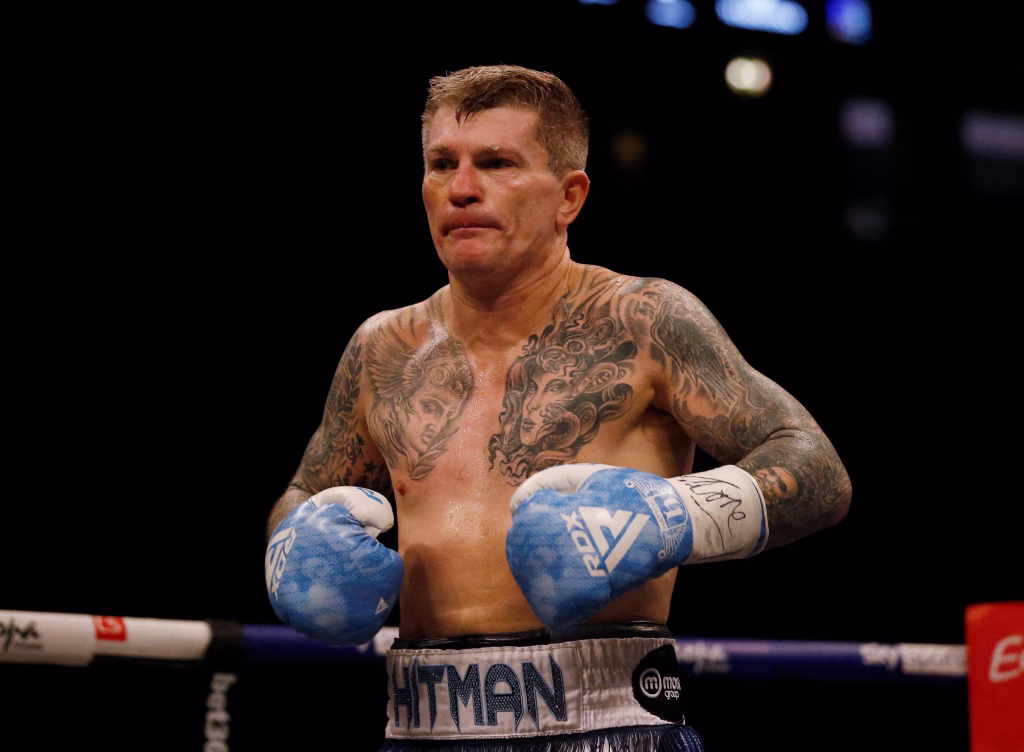 Ricky Hatton in his prime, wearing blue trunks and gloves, delivering a powerful punch during a boxing match.