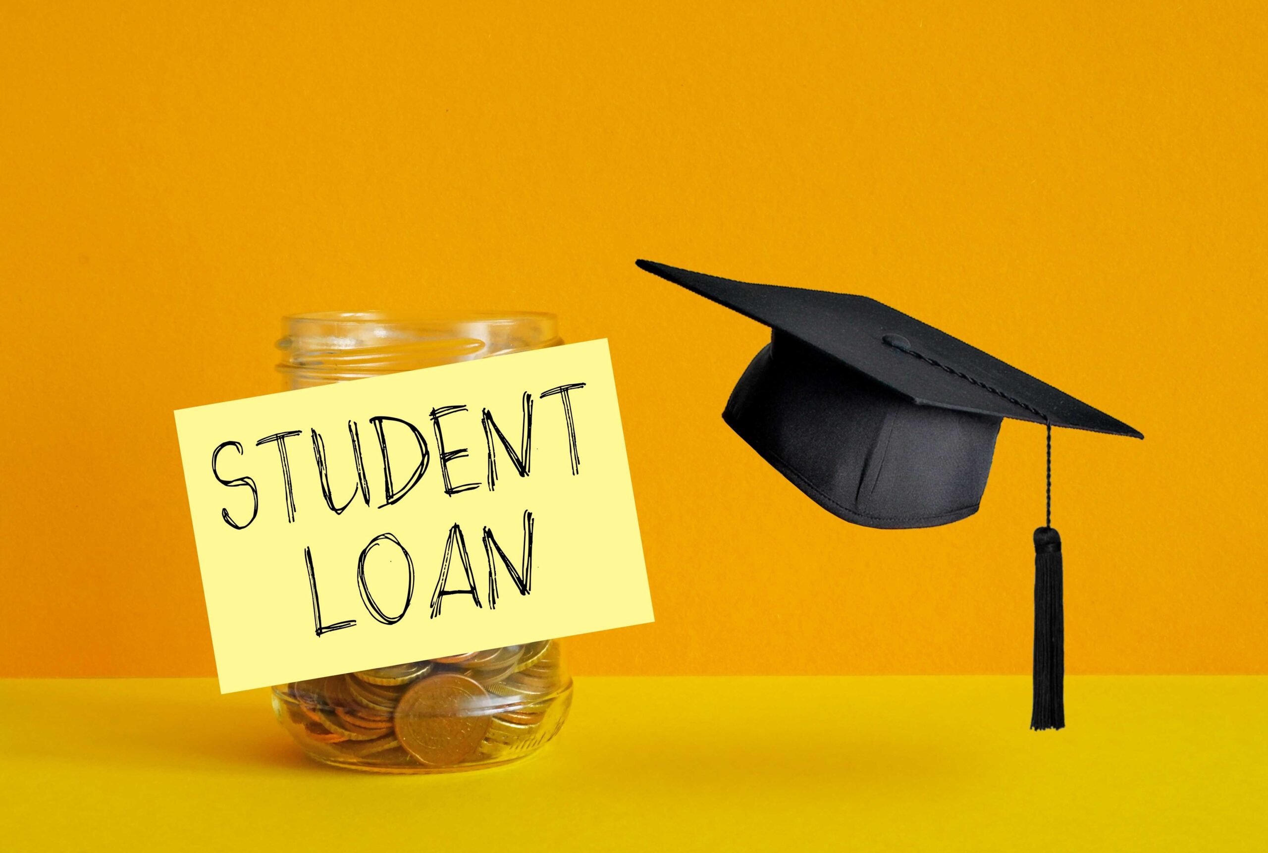A graduation cap placed next to a jar labeled “Student Loan Savings,” symbolizing planning and saving for student loan repayment.