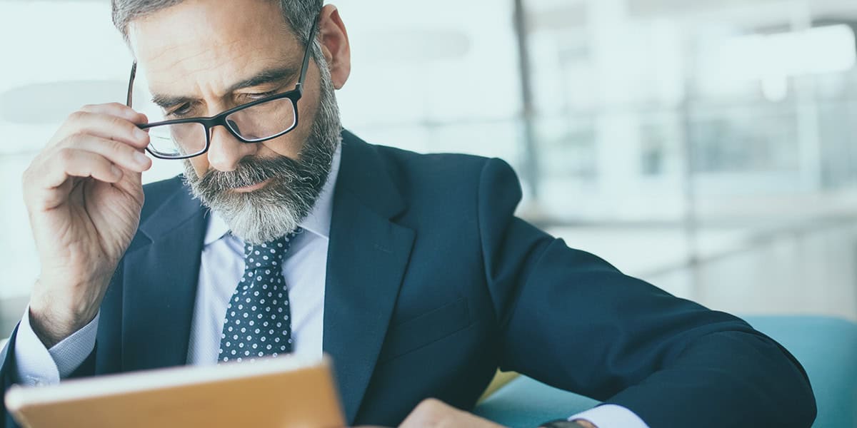 CEO reviewing financial documents and reports at his office desk.