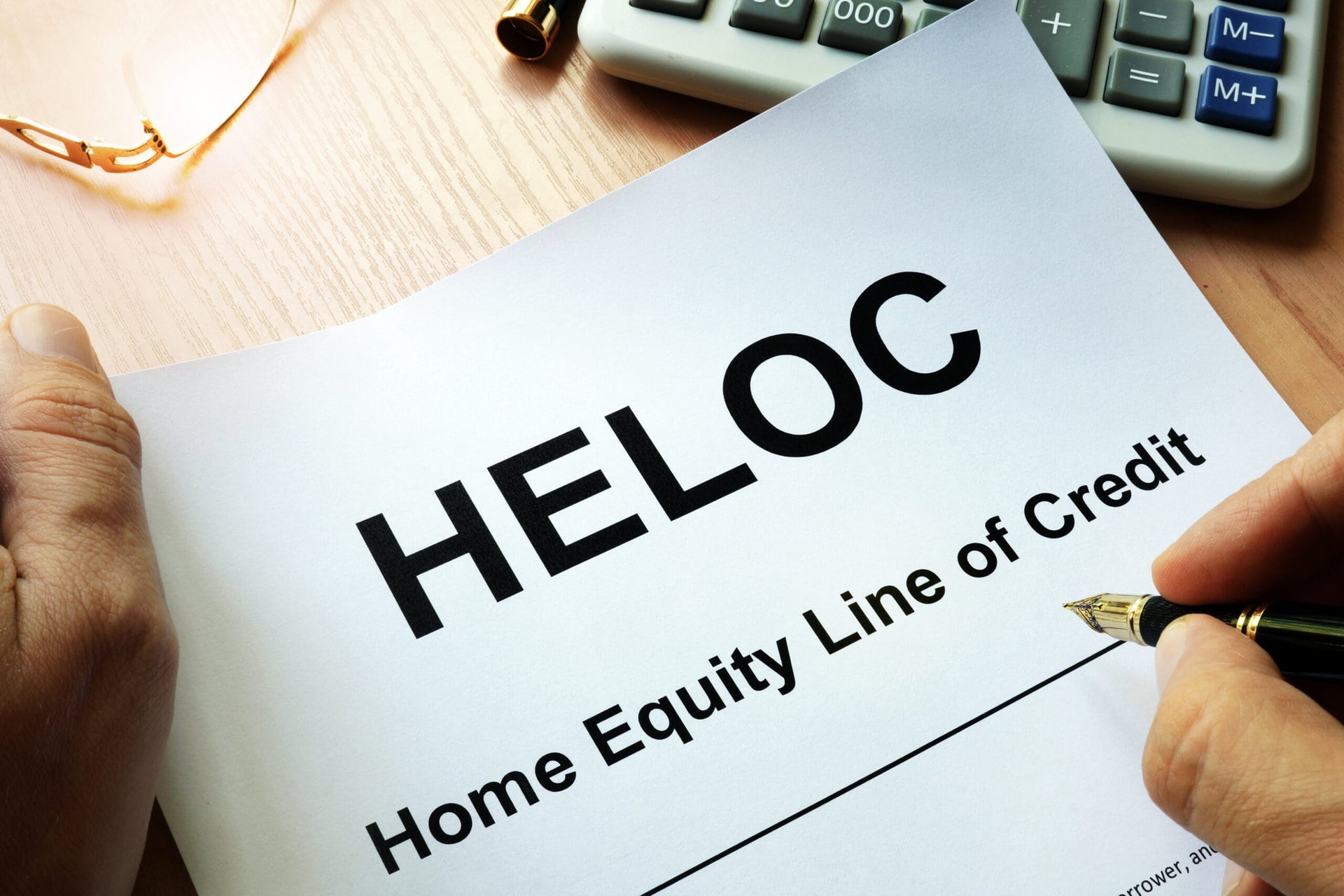 A close-up of a HELOC (Home Equity Line of Credit) loan document with highlighted terms and a pen resting on top.