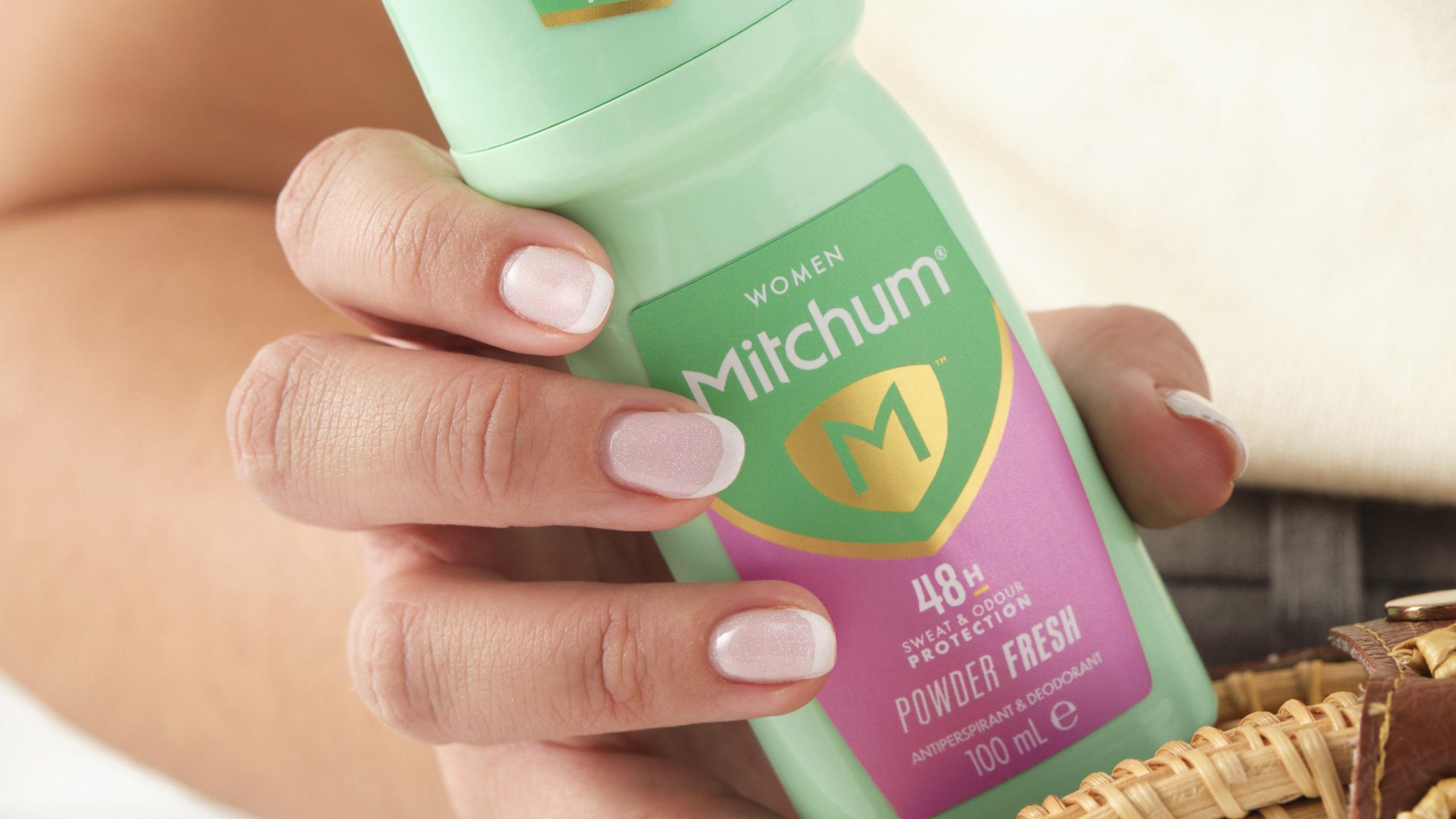Woman holding a Mitchum 100ml roll-on deodorant affected by the recent recall.