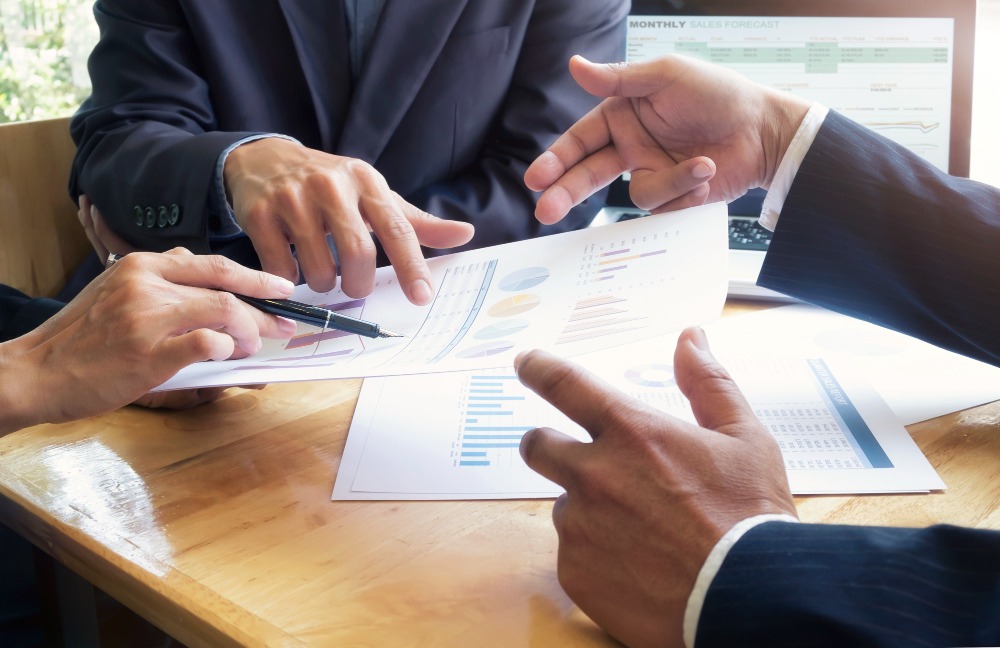 Group of business professionals sitting around a table with documents, discussing financing options for their company.