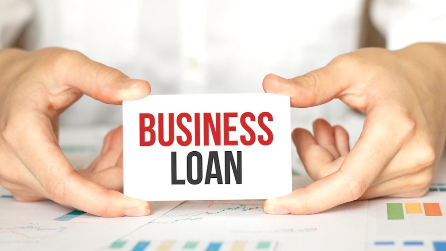 Businessman holding a small card labeled “Business Loan,” symbolizing access to business financing.