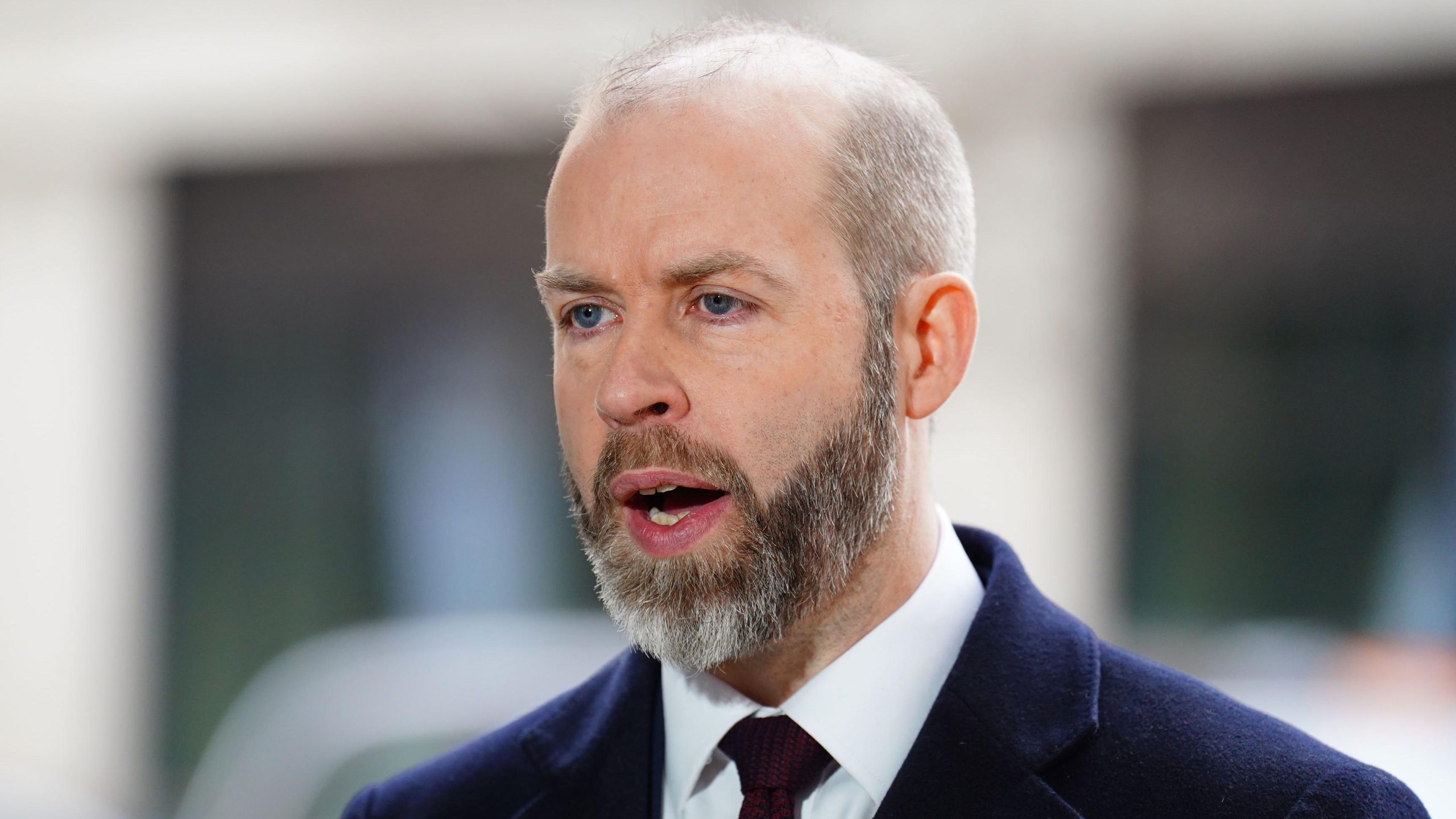 Jonathan Reynolds being interviewed by the BBC outdoors, speaking into a microphone with a small crowd and cameras in the background.