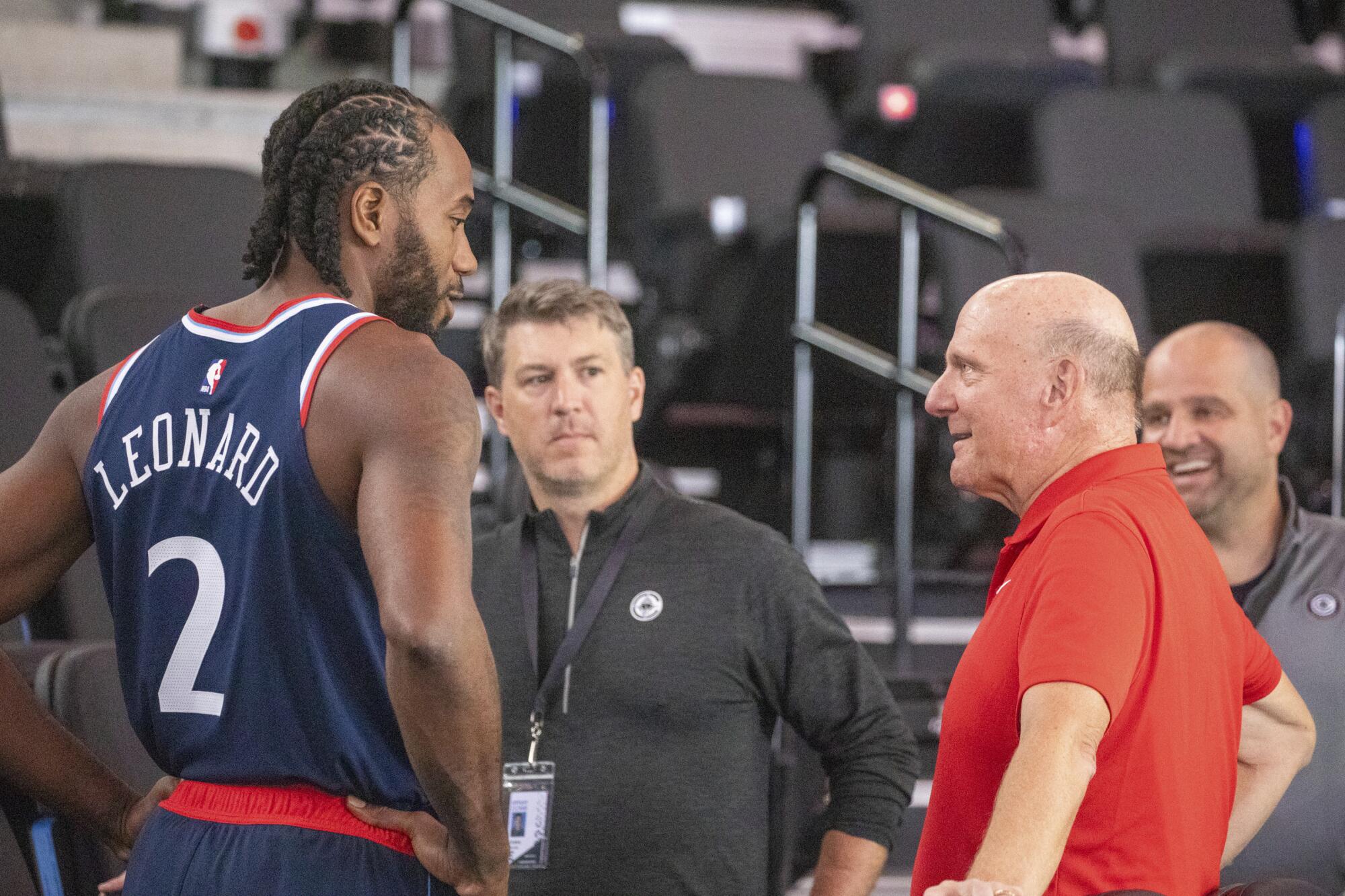 Kawhi Leonard on the sidelines, conversing with Clippers owner Steve Ballmer during a game.