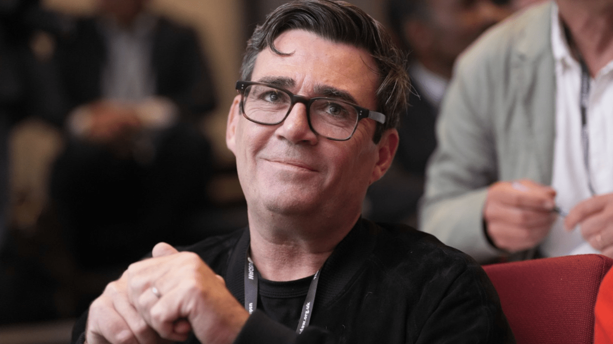 Andy Burnham sitting in an audience and smiling, showcasing his approachable and engaged demeanor as Mayor of Greater Manchester.