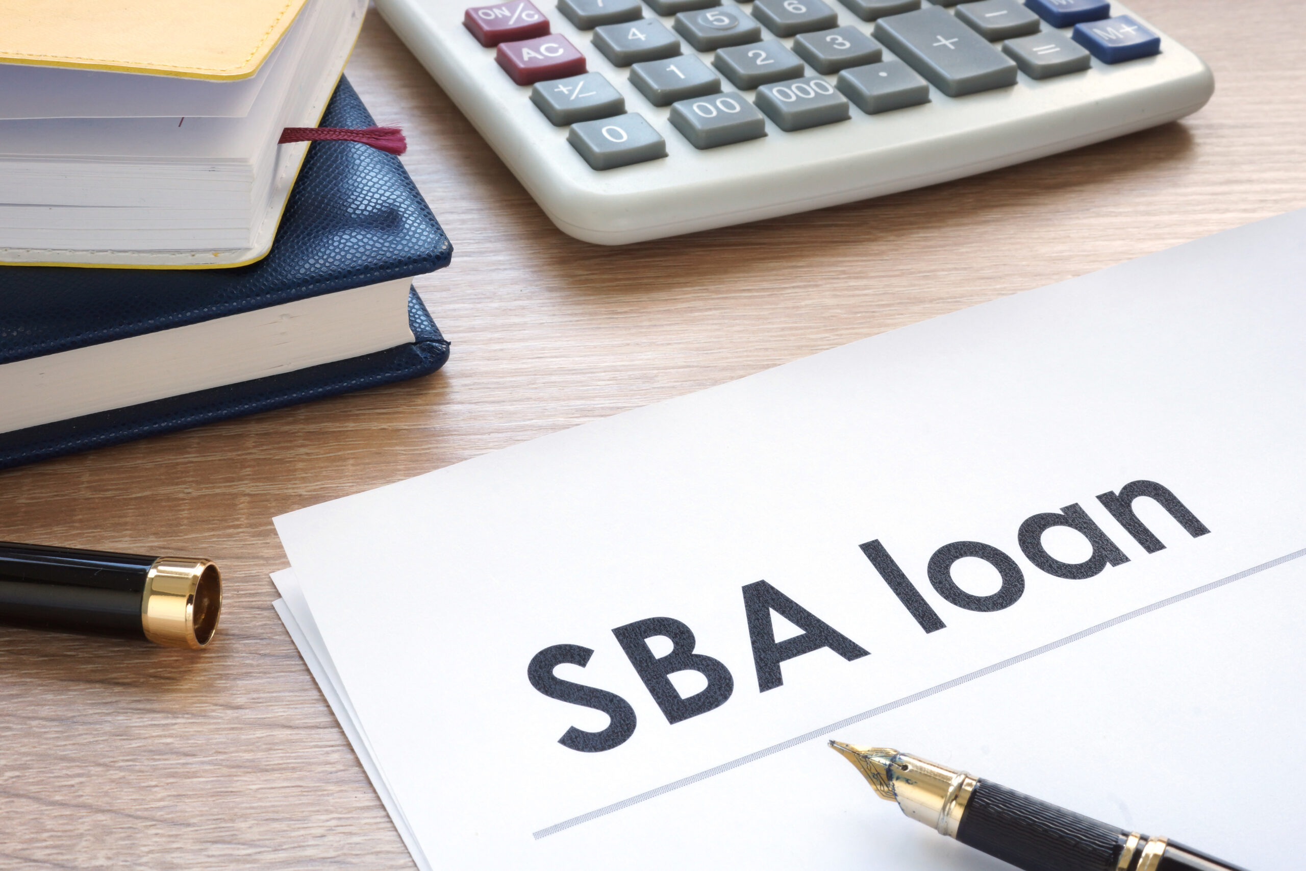 SBA loan application document on a desk with a pen ready for signing.