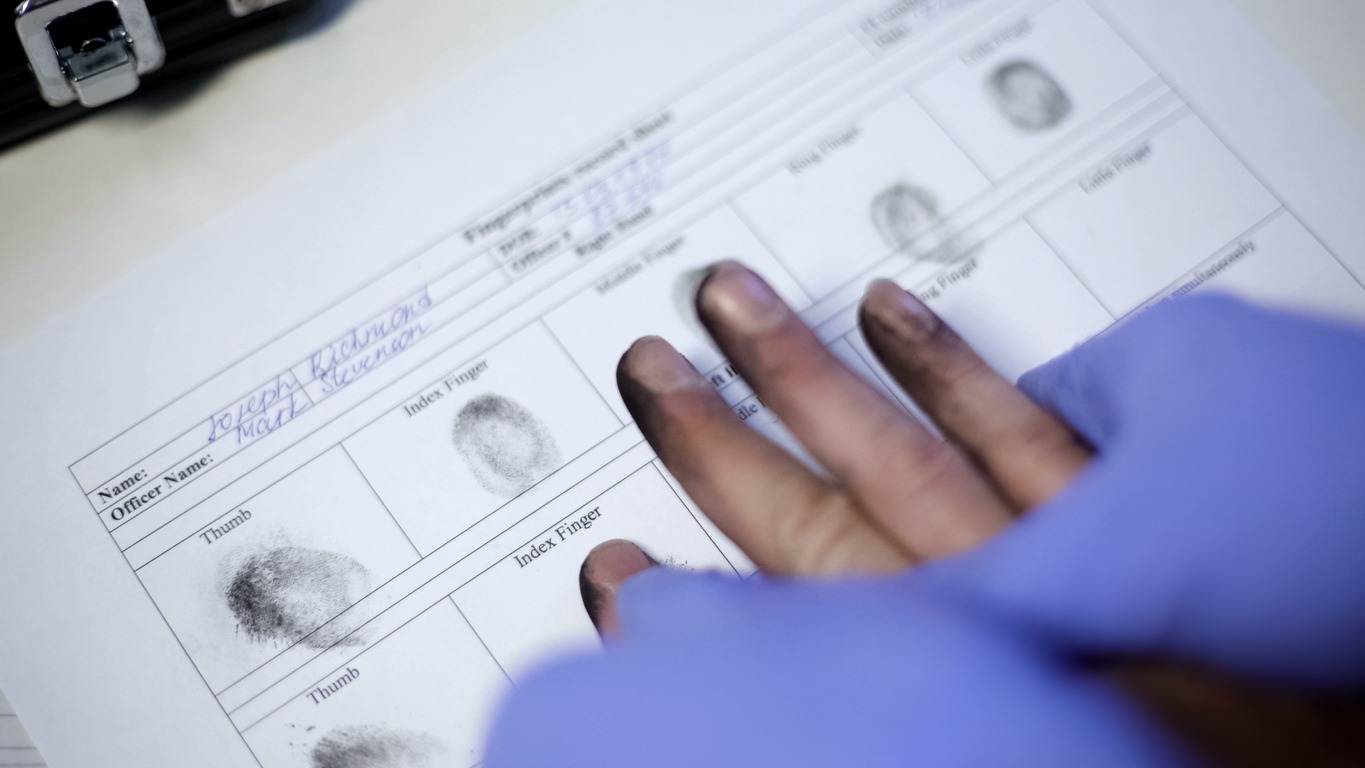 police officer in exam gloves taking fingerprints from suspect, hands closeup
