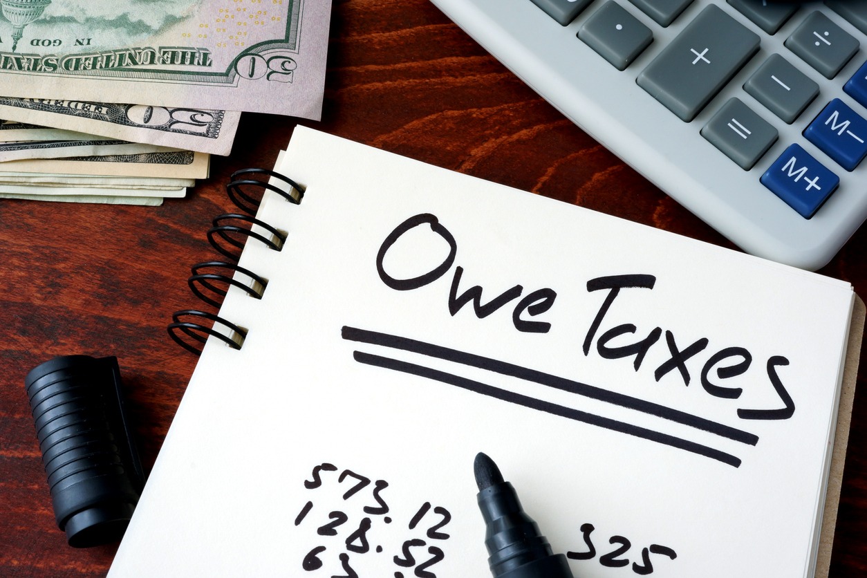 notepad with sign owe taxes on a wooden background.