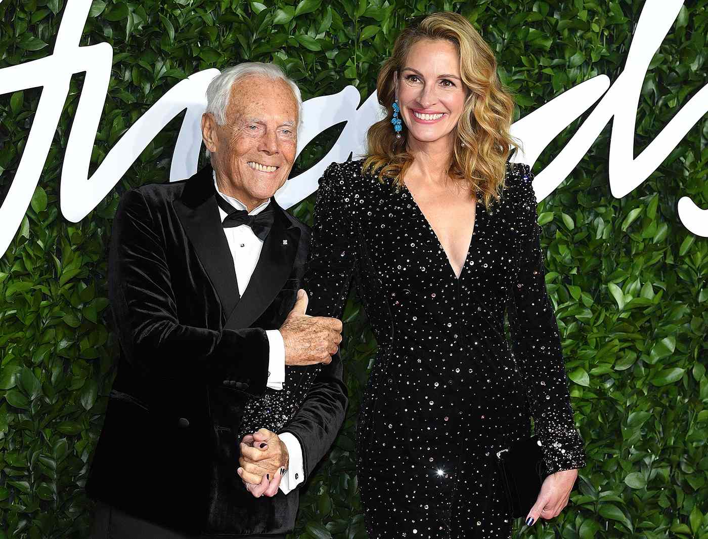 Giorgio Armani posing on the red carpet alongside Julia Roberts, both dressed elegantly for a high-profile event.