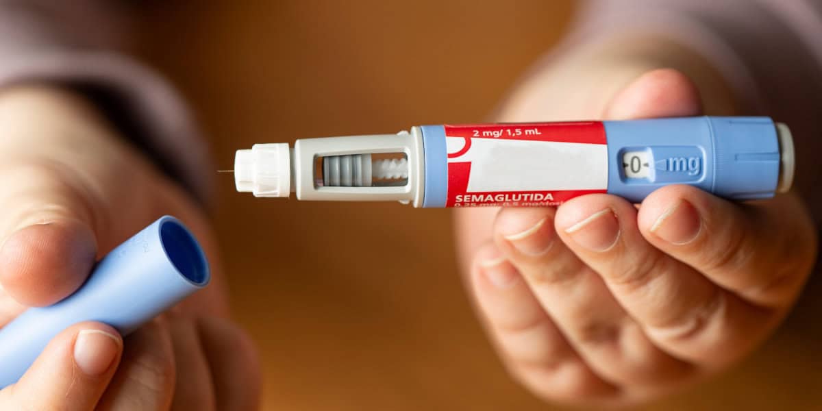 Person holding an Ozempic injection pen used for diabetes and weight-loss treatment.