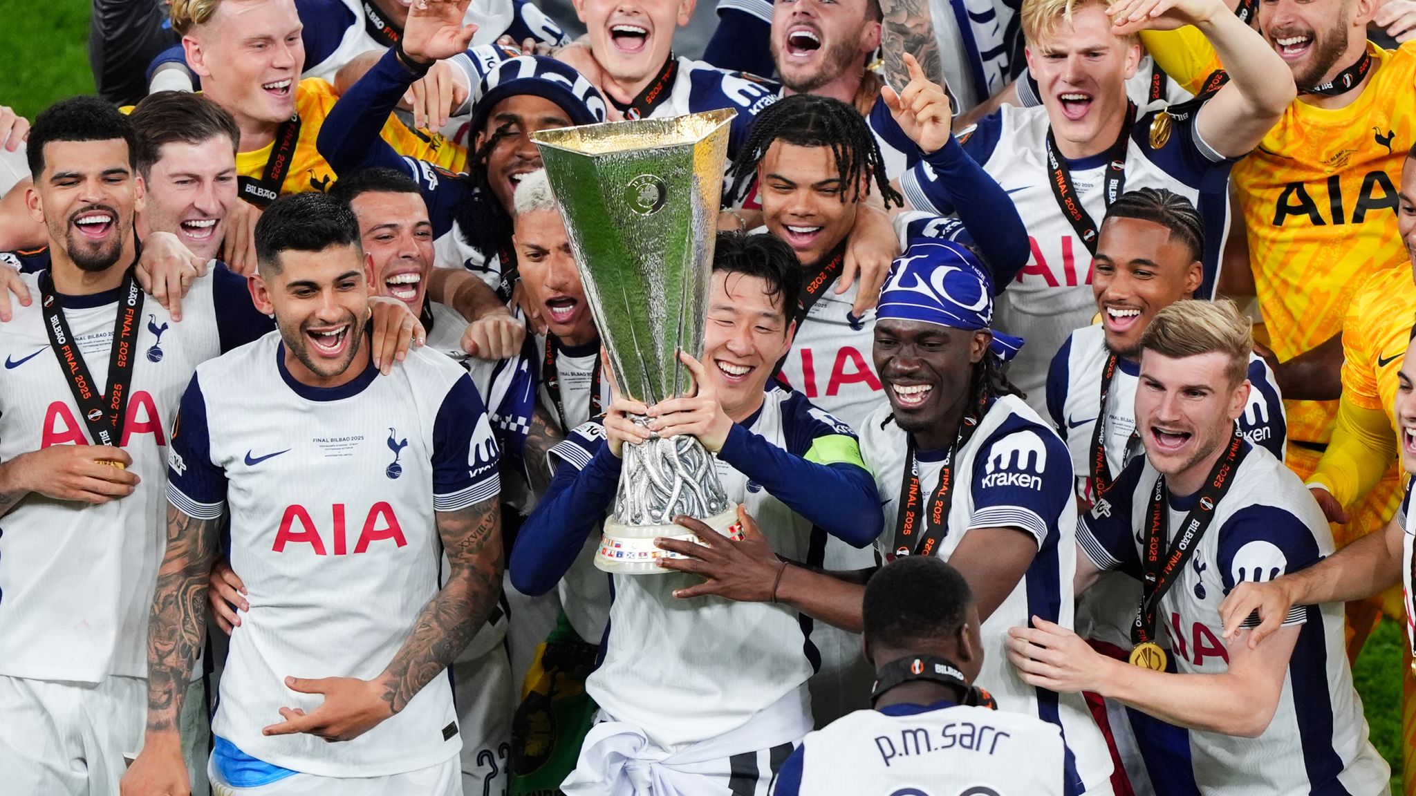 Tottenham Hotspur players lifting the UEFA Europa League trophy, celebrating their victory on the pitch.