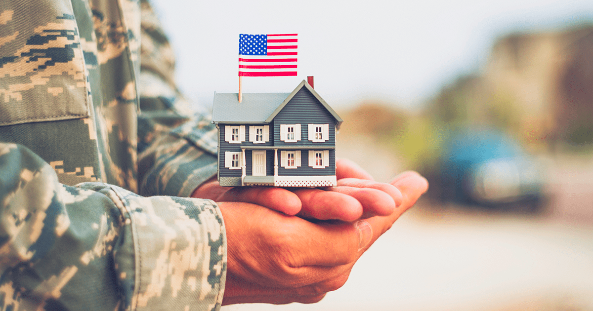 U.S. veteran holding a small model house, symbolizing homeownership through a VA loan.