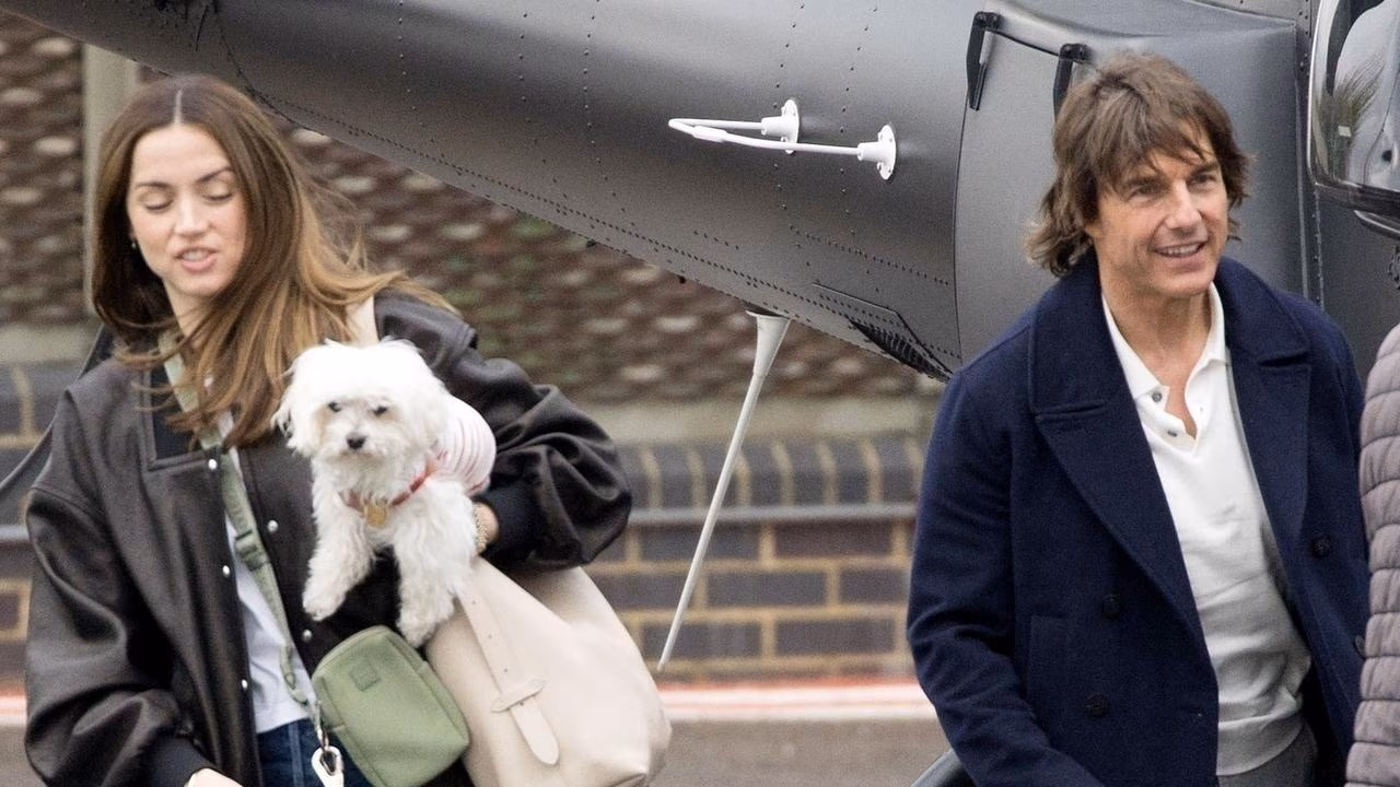Ana de Armas and Tom Cruise exiting a helicopter, holding a white dog