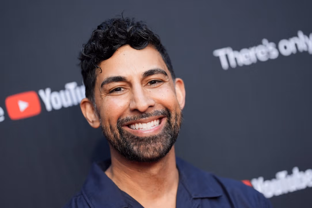 Dhar Mann smiling and posing on the red carpet at a YouTube event, dressed formally and interacting with fans and media.