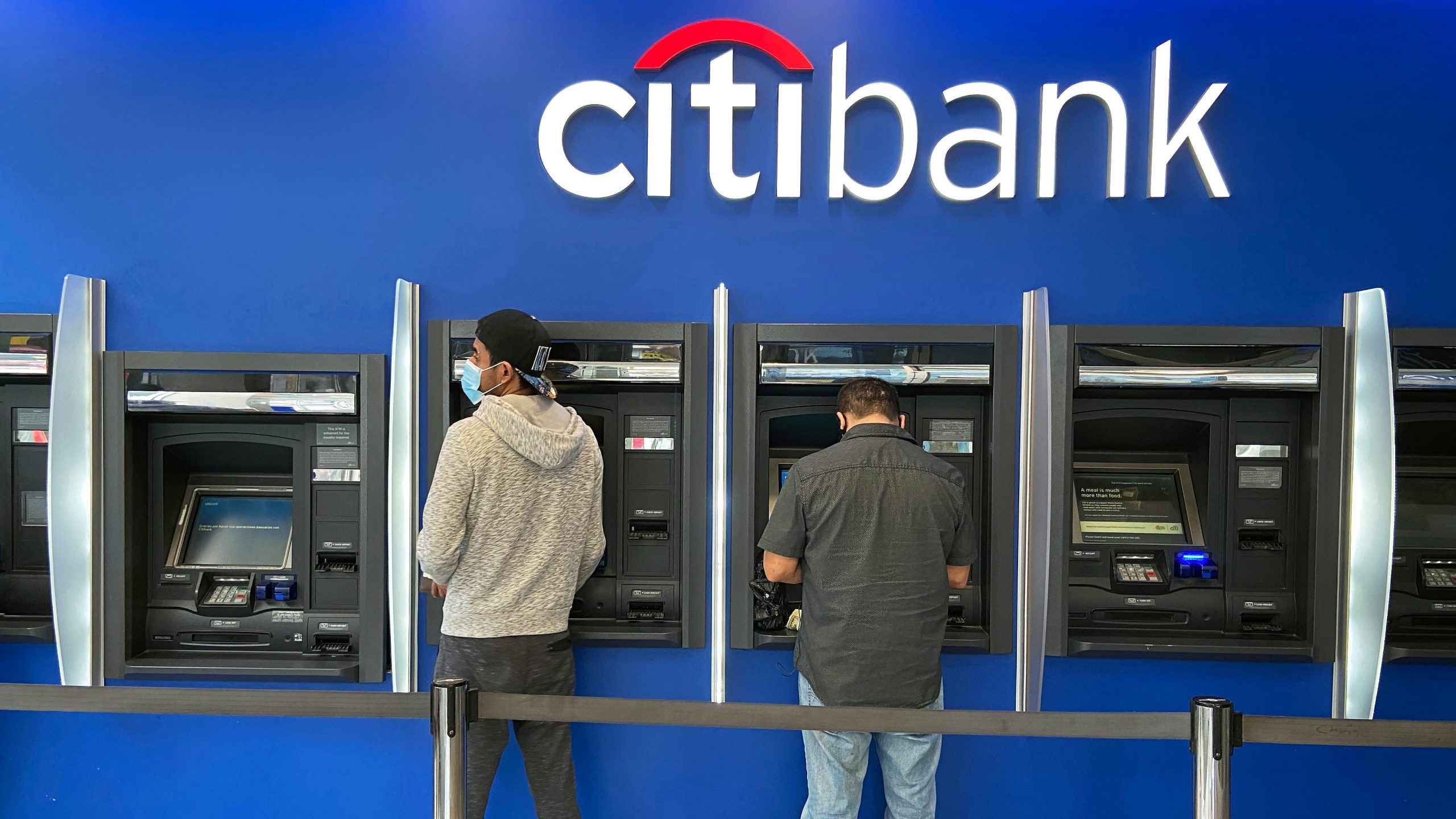 Customers withdrawing cash from Citibank ATMs in a busy urban location.