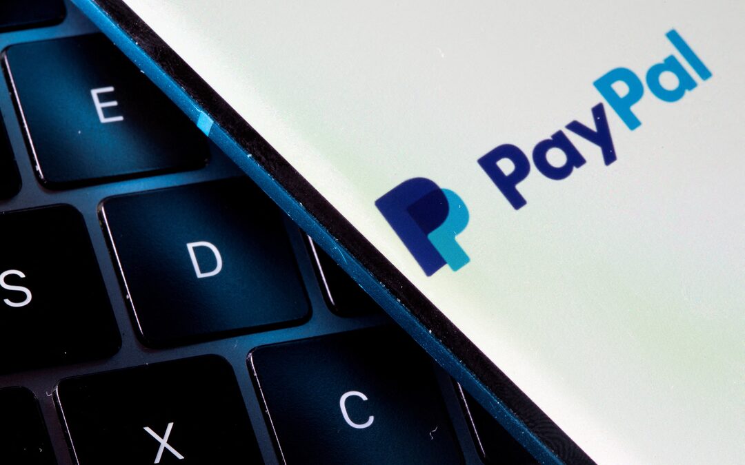PayPal app displayed on a smartphone screen next to a computer keyboard.