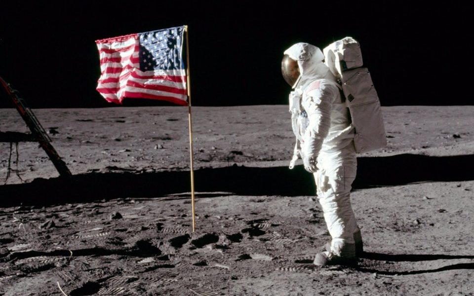 Buzz Aldrin standing on the lunar surface next to the American flag during the 1969 Apollo 11 moon landing.