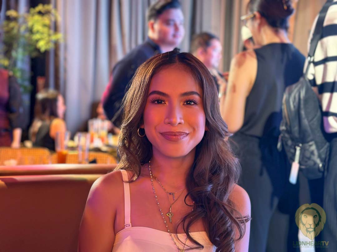 Emman Atienza smiling for a photo while seated in a restaurant.