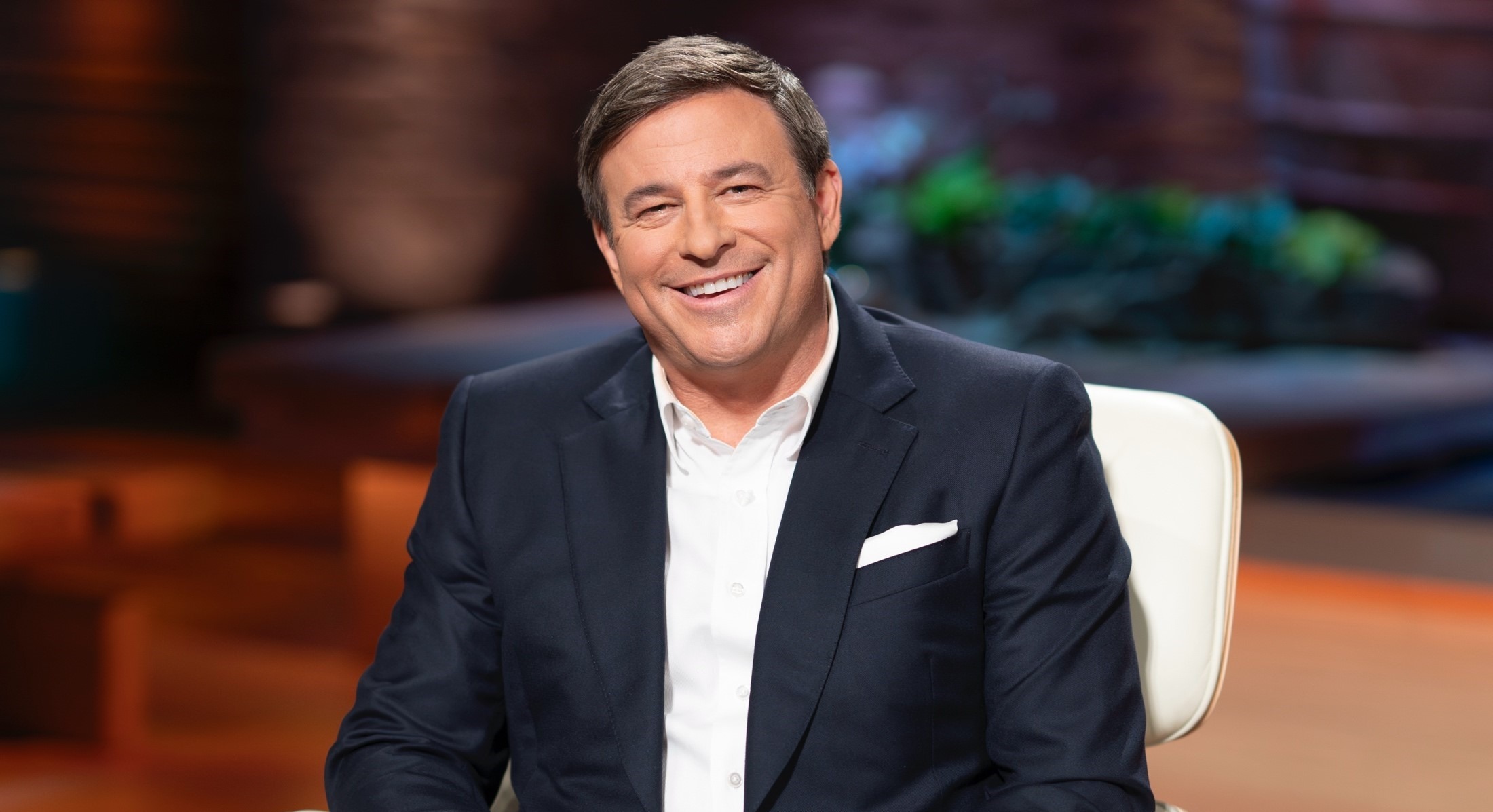Todd Graves dressed in a sharp suit during a live interview in a news studio, speaking confidently under bright studio lights.