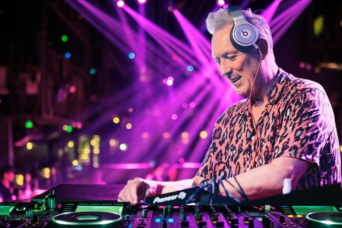 Martin Kemp DJing on stage under vibrant neon lights, energizing the crowd.