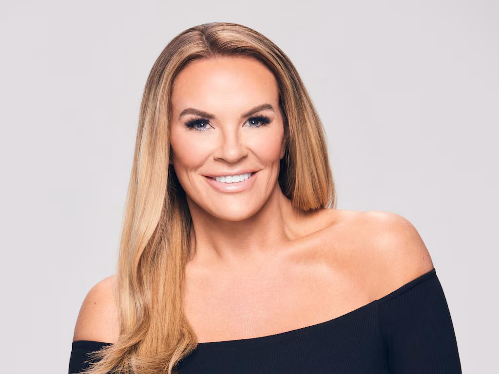 Heather Gay smiling in a black dress during a professional photoshoot, exuding confidence and elegance.