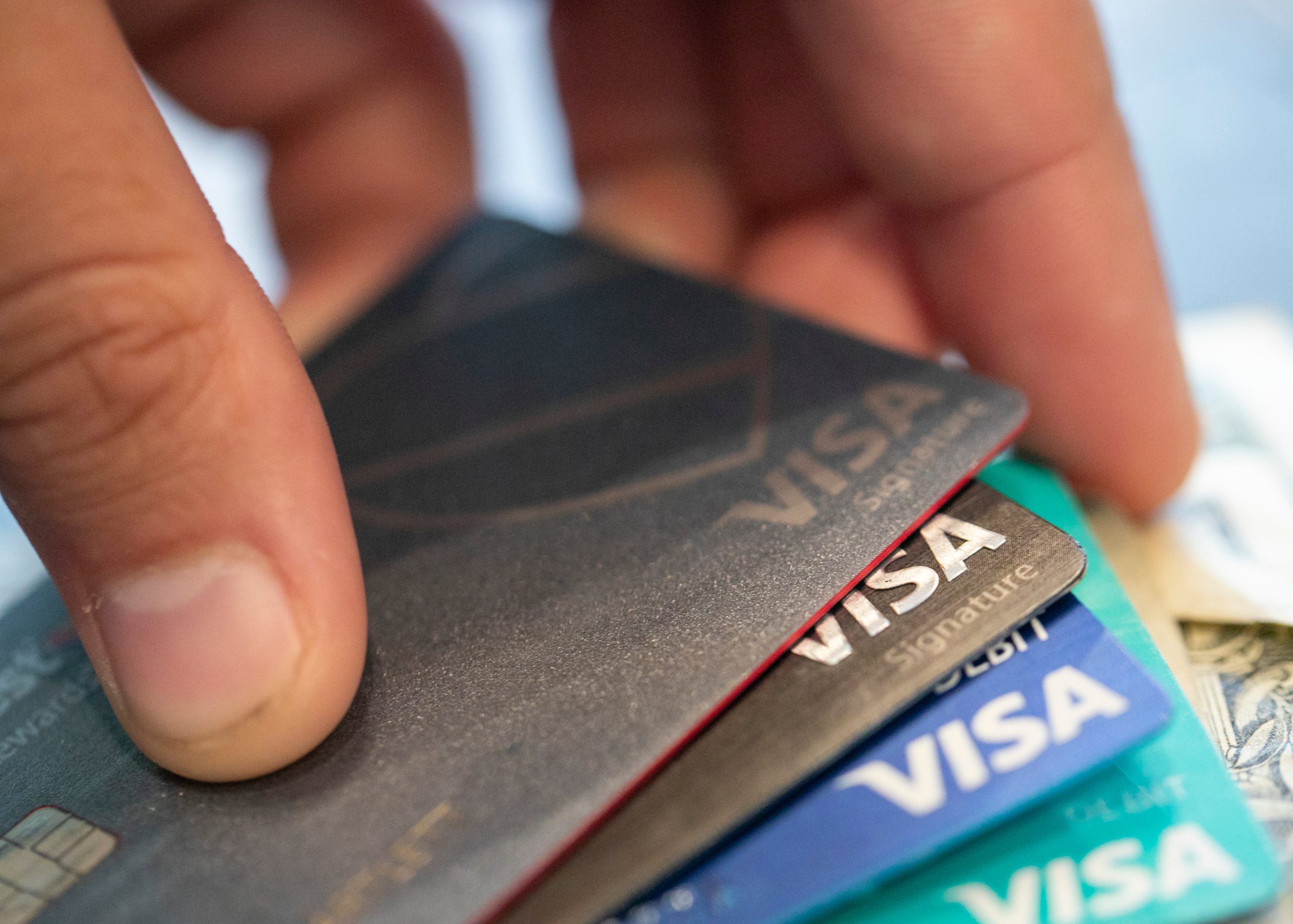 A hand holding multiple credit cards of different designs and colors, symbolizing credit use and debt management.