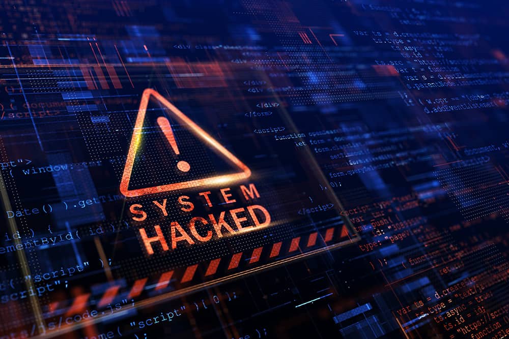 Warning sign on a computer screen reading "System Hacked" surrounded by digital code, symbolizing major UK cyberattacks and ransomware breaches in 2025.